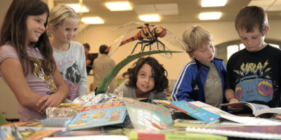 Kinder schauen fasziniert das Modell eines Insekts an